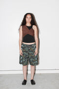 Person wearing a sleeveless top and camouflage shorts with white patterns on a white background