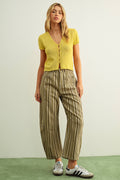 Woman wearing a yellow top and striped pants against a plain background