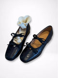 Black ballet flats with a white sock on a light gray background