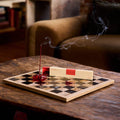 Incense stick on a chessboard with smoke, placed on a wooden table.