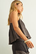 Woman wearing a sleeveless top and pants on a plain background
