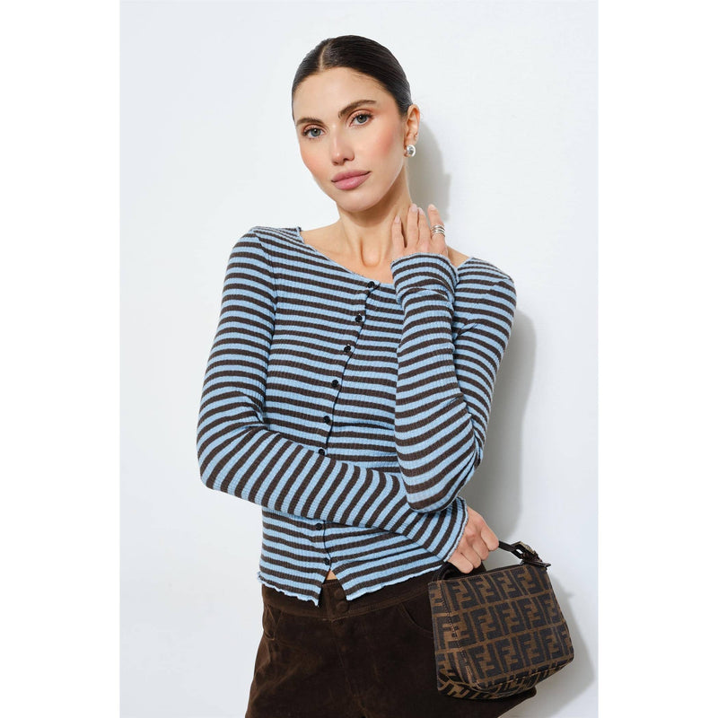 Woman wearing a striped sweater holding a handbag against a white background
