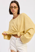 Woman wearing a yellow ribbed sweater and white jeans on a white background