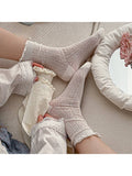 Person wearing lace-trimmed socks on a couch