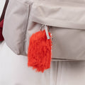 Red fluffy keychain attached to a beige jacket