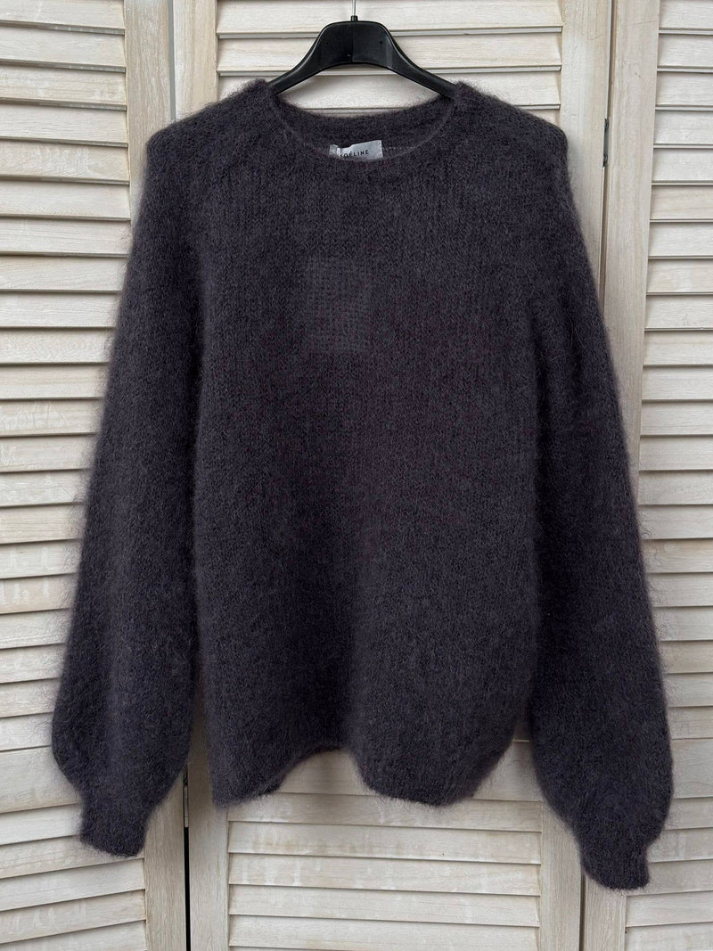 Dark gray sweater on a hanger against a wooden panel background