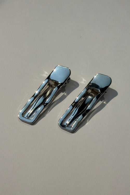 Two silver metal hair claw clips with a polished chrome finish, displayed on a neutral light gray background.