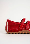 A close-up side view of a red perforated Mary Jane-style shoe with two red straps and a tan sole, photographed on a clean white background.