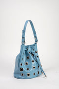 A light blue leather bucket bag with silver-tone metal grommets and a drawstring closure, shown on a plain white studio background.