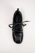 A single black leather sneaker shown from a top-down view, featuring black laces and contrasting white piping details on the toe and side, set against a plain white background.