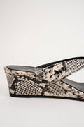 A close-up side view of a wedge mule sandal featuring a black and beige snakeskin pattern on the wedge and strap, with a black insole.