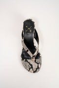 A single women's heeled sandal shown from a top-down view on a light gray background. The sandal features a snakeskin-patterned strap and toe cap with black heel counter and a small gold-tone metal accent at the center.