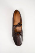 A single dark brown leather ballet flat shoe with a pointed toe and decorative bow details, photographed from a top-down perspective on a clean white background.