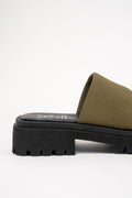 An olive green slide sandal with a thick, chunky black lug sole, shown from a side profile view against a plain white background.