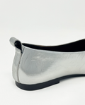Silver flat shoe with black sole on a white background