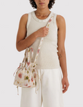 Person holding a floral drawstring bag against a white background