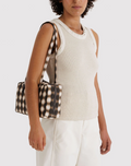 Person holding a patterned clutch bag against a white background
