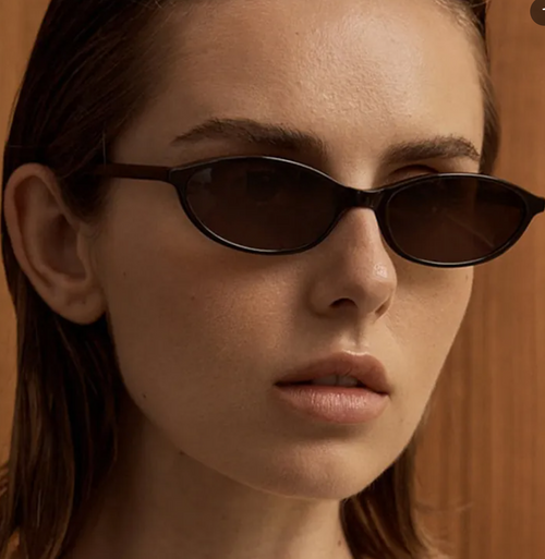 Close-up of a person wearing dark sunglasses with a blurred background