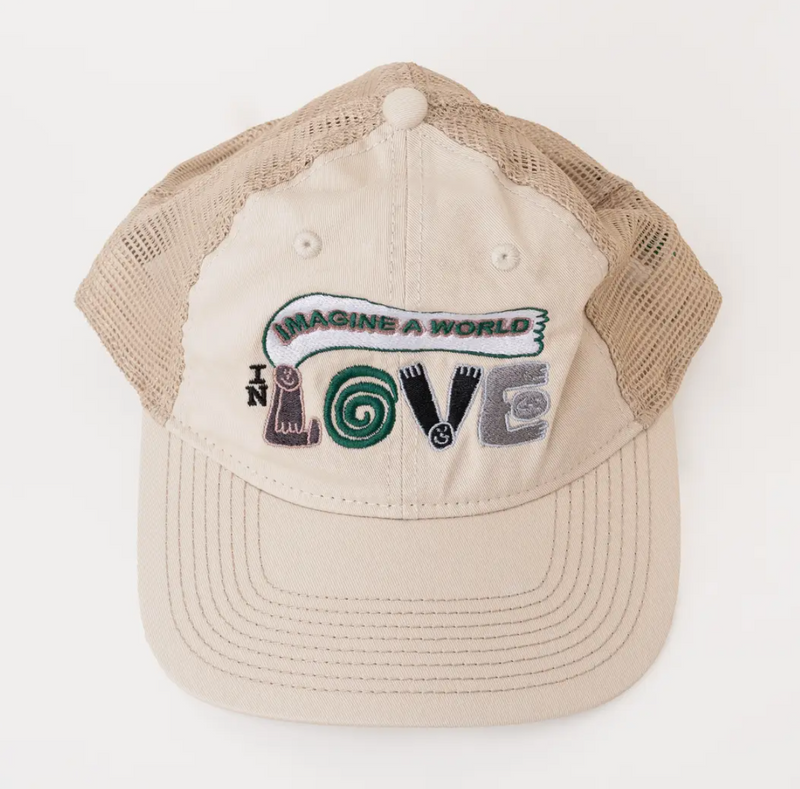 A beige trucker hat with a curved brim, featuring a colorful embroidered graphic on the front panel that reads 'IMAGINE A WORLD LOVE' with stylized letters.