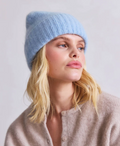 Woman wearing a light blue knit beanie against a plain background