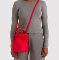 Person wearing a gray outfit with a red drawstring bag on a white background