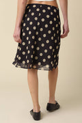 Black polka dot skirt worn by a person on a beige background