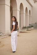 Woman standing in front of a building with arches and potted plants.