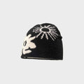 Black knit beanie with white floral pattern on a light gray background