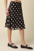 Black polka dot skirt worn by a person on a beige background