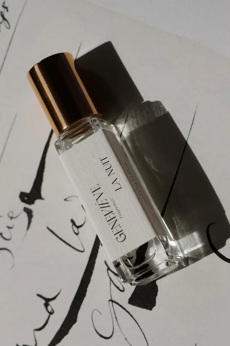 Perfume bottle labeled 'Geneve' on a sheet of music with cursive writing.