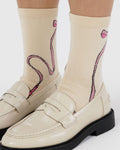 Beige loafers with pink bow design socks on a white background