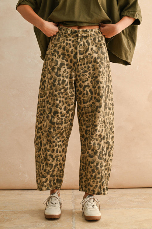 Person wearing leopard print pants and an olive green top against a beige background