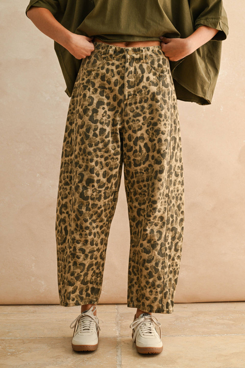 Person wearing leopard print pants and an olive green top against a beige background