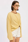 Woman wearing a yellow striped sweater and white shorts on a plain background