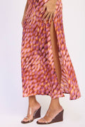 Person wearing a patterned dress with a slit and clear wedge sandals on a white background