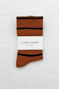 Brown sock with black stripes and 'Le Bon Shoppe' label on a light gray background