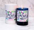 Two candles with colorful 'SMOKE' labels on a marble surface