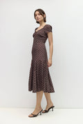 Woman wearing a brown polka dot dress against a white background