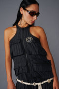 Woman wearing a black layered vest with a gray background