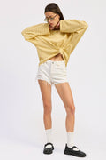 Woman wearing a yellow striped sweater and white shorts on a white background