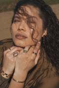 woman wearing Gold ring with a central blue gemstone 