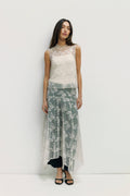 Woman wearing a sleeveless lace top and floral skirt on a white background