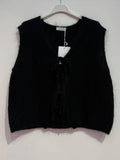 Black knitted vest on a hanger against a white background