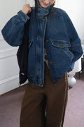 Person wearing a blue denim jacket and brown pants indoors.