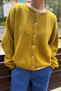 Person wearing a yellow cardigan and blue pants outdoors