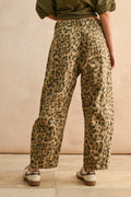 Person wearing leopard print pants against a beige background