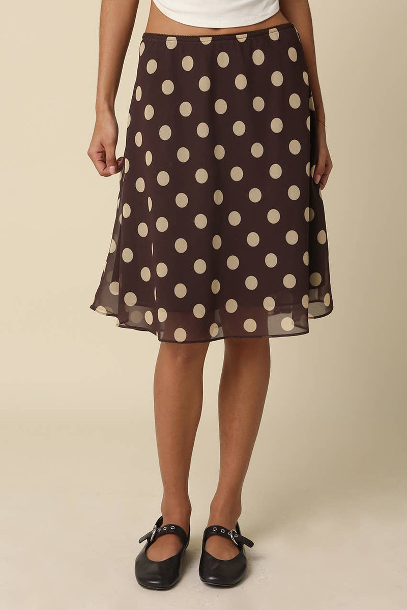 Woman wearing a brown polka dot skirt on a beige background