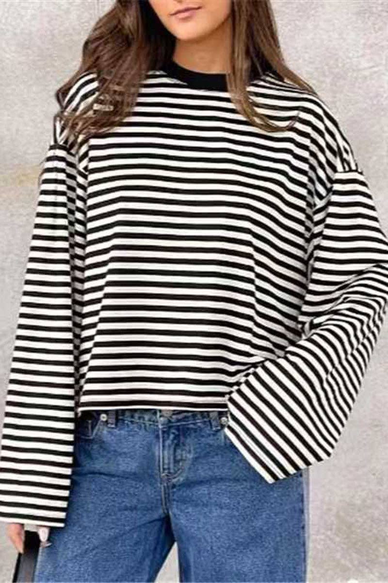 A woman wearing a black and white horizontally striped long-sleeve top with a black crew neck, paired with blue jeans.