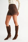 Brown knee-high boots worn with brown shorts on a white background