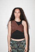 Woman wearing a brown and black sleeveless top with camouflage pants on a white background